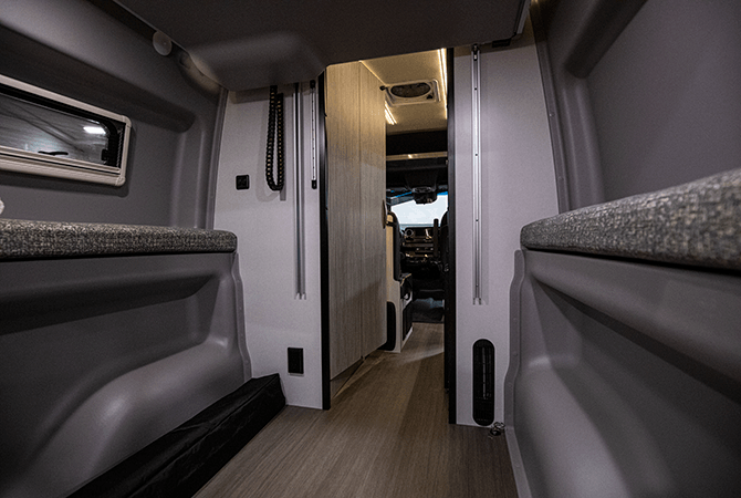 A photo from the rear of the Winnebago Revel 44E Class B RV Camper Van shows the power lift bed raised to reveal the large garage area.