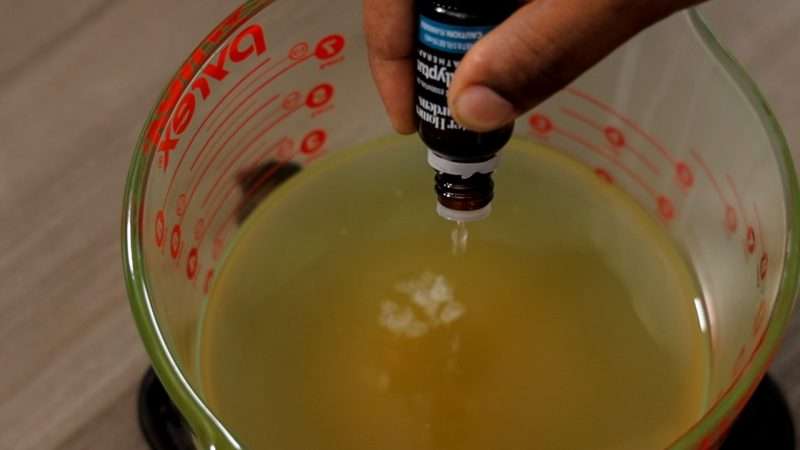 Drops of essential oil are added to a large glass Pyrex measuring cup that contains melted max.