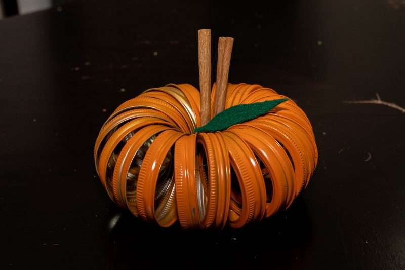 A pumpkin made out of mason jar lids painted orange and strung together with wire.