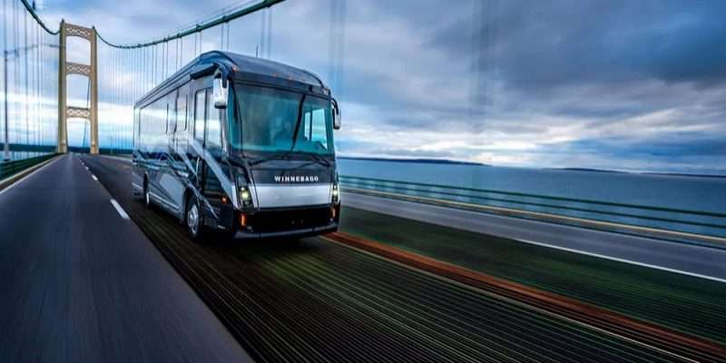 A Winnebago Journey Class A motorhome travels along a suspension bridge.