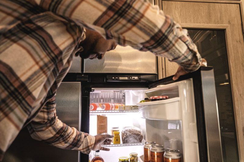 A man reaching for a snack in the refrigerator of the RV.